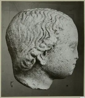 Carved stone head with wavy hair and a curled lock above the ear, from Mersinaki