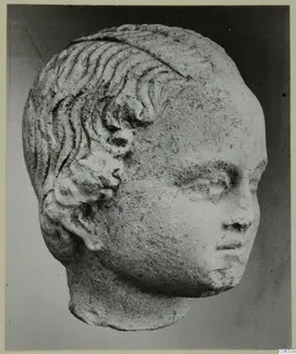 Carved stone head with wavy incised hair and curls above the ear, from Mersinaki.