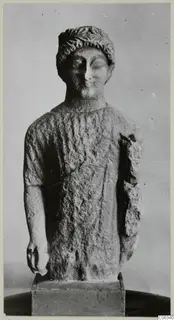 Limestone statue from Kition of a standing figure with a leafy band in its hair, one arm broken away at the shoulder