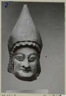 Limestone head statue from Kition with a tall conical headdress and a faint smile
