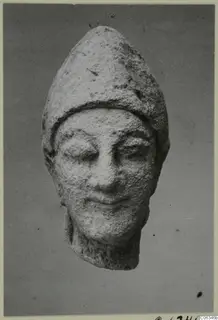 Limestone head fragment from Kition with a tall pointed cap, seen from the front