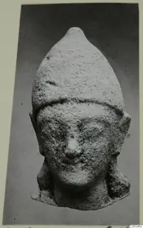 Limestone head of a figure with a tall pointed headdress, from Kition, shown frontally