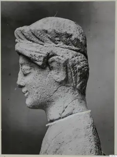 Limestone head sculpture in profile facing left, with a band over the hair and a neck that is cracked and joined