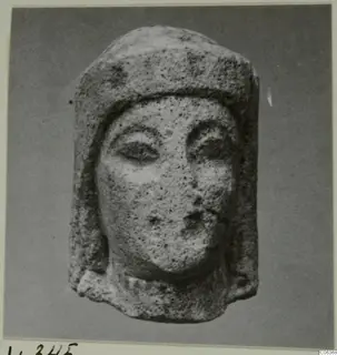 Limestone head from Vouni wearing a close-fitting headdress, with large almond-shaped eyes and a small mouth