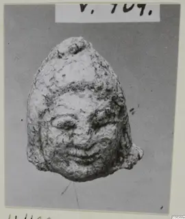 Small limestone head from Vouni with a worn face, almond eyes and a smiling mouth