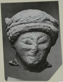 Limestone head from Vouni with a thick banded headdress, shown in a photograph on a card mount.