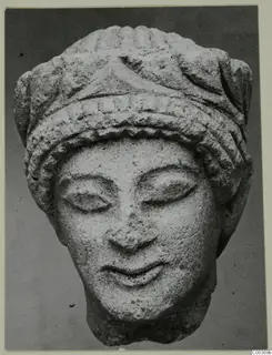 Limestone head from Vouni with downcast eyes and a ridged headdress, shown from the front