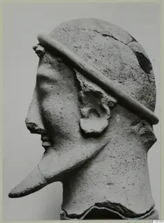 Terracotta head sculpture in profile facing left, with a band across the crown and a long pointed projection from the lower face