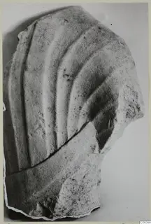 Limestone sculpture fragment from Vouni with carved curving folds, broken along its lower edge