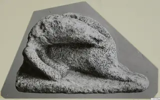 Limestone minor plastic figure, a small pitted stone carving with a curved projection resting on a flat base