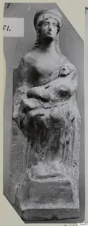 Terracotta figurine of a female figure in a tall headdress, holding a small figure or object against her chest.