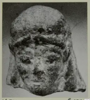 Front view of a small head with a broad band across the brow and a broken lower edge, mounted on a card