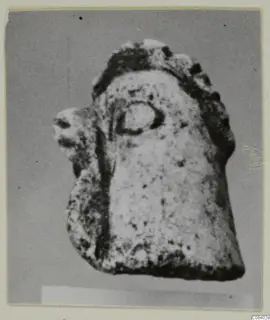 Small limestone figurine fragment with a rounded, head-like top and a projection on the left side.