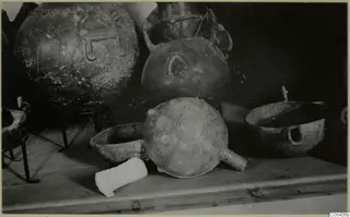 Several pottery vessels on a wooden shelf at the Cyprus Museum, including a bowl with a radiating painted pattern