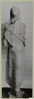 Back view of a limestone statue of a standing figure in a long draped garment, from Vouni
