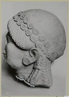 Limestone head from Vouni, shown in profile facing left, with curled hair and an ear ornament