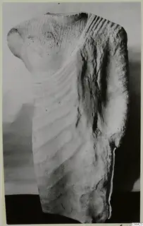 Limestone sculpture fragment from Vouni: upper torso of a figure with carved drapery folds and grooved shoulders.