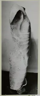 Fragmentary limestone sculpture of a figure's torso, broken at the top and base