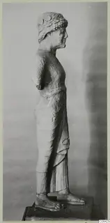 Limestone statue of a standing figure in profile, Kition, wearing a wreath and long draped garment with sandals