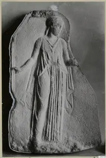 Marble relief plaque of a standing female figure in a long draped garment, with vertical folds