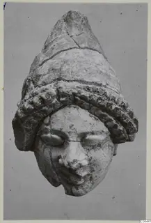 Limestone head sculpture from Vouni wearing a tall conical headdress with a ridged band, shown frontally
