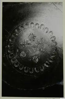 Close view of the inside of a black-glazed vessel with impressed scallop and flower decoration