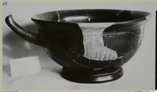 Black-glazed kylix with a single curved handle and vertical ribbing on the lower body
