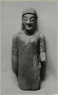 Limestone statuette of a standing figure in a long draped garment, from Kition; one forearm broken off.