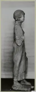 Side view of a limestone statue of a standing woman in a long pleated garment, from Vouni.