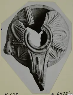 Terracotta lamp with radiating ridged decoration, a small head at the left and a large ring-shaped filling hole at the centre.