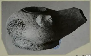 Terracotta lamp with a round filling hole and a pointed spout, shown on a grey mount