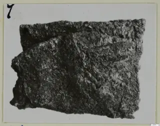 Corroded bronze fragment from Kition, shown as a photograph mounted on card