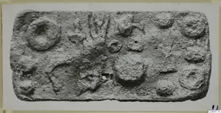 Rectangular lead plaque with raised round impressions and a small hole near the lower centre