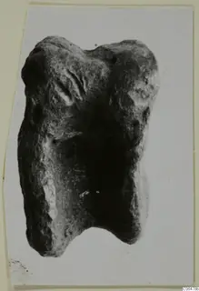 Lead fragment from Kition: a lumpy grey object with a notch in its lower edge, photographed on a card mount.