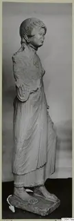 Limestone statue of a standing woman from Vouni, shown from the side on a rectangular base.