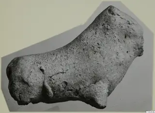 Terracotta figurine of a small animal, shown in side view on a grey mount
