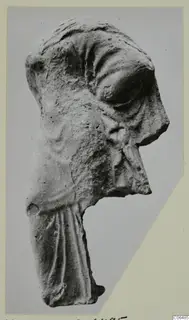 Terracotta figurine fragment of a head in profile facing right, with draped garment below, from Kition