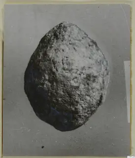 Rounded lump of lead with a pitted grey surface and blue-tinged patches, photographed on a plain grey background.