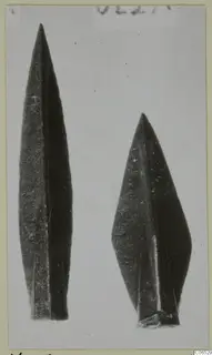 Two pointed weapon blades photographed side by side on a pale background, one longer and narrower than the other.