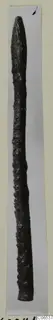 Bronze pin with a pointed top, photographed against a pale background