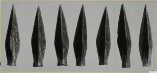 Bronze Age weapon points from Vouni, a row of pointed leaf-shaped blades photographed on a grey ground