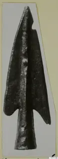 Bronze barbed point from Vouni, shown on a pale card mount