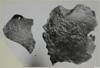Two corroded bronze fragments from Vouni, one smaller piece with a small hole near its top edge