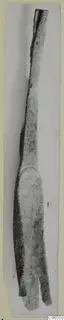 Long bronze implement with a slender shaft and a flattened, split end, shown on a card mount