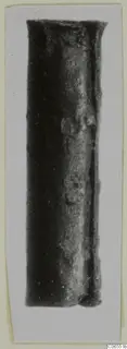 Bronze fragment, a dark cylindrical metal piece with a flared top rim, photographed upright