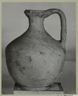 Pottery Plain White VII jug with one handle and a rounded body, shown on a stand