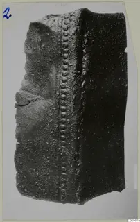 Corroded bronze fragment with a raised ridge of rounded studs running down one face