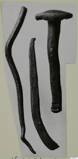 Three dark, corroded metal objects: a nail with a flat round head and two long slender rods