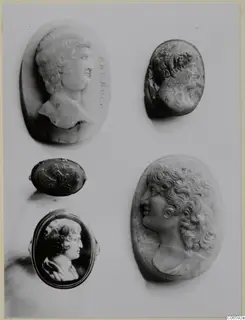 Five carved gems and cameos on a pale mount, most showing male or female heads in profile.
