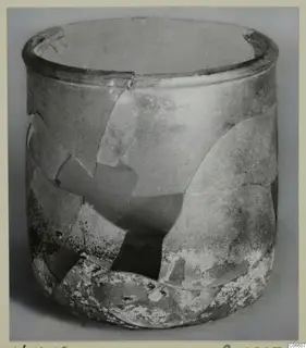 Blown glass vessel from Vouni, reconstructed from fragments and photographed against a grey background.